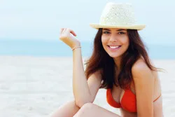 Model at beach in red bikini top and hat