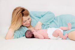 Smiling Mother Laying Next to Baby