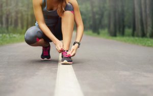 Female Kneeling to Tie Shoe on Road