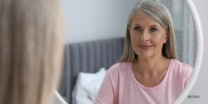 woman looking at her reflection in the mirror after a facelift procedure